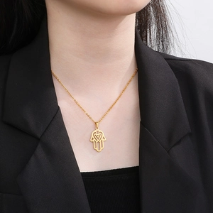 Detail of 18K gold plated Hamsa hand pendant with heart cutout worn by model