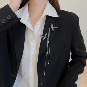 Detail shot of a silver phoenix brooch with pearls on a black suit jacket lapel