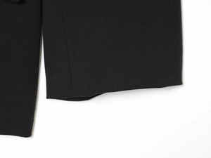 Gros plan de la manche du blazer noir montrant la texture sergée et les coutures nettes