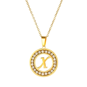 Detail of a gold circular pendant featuring letter X with sparkling zircon stone inlay