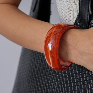 Close-up of a wide translucent red resin geometric bangle on a female wrist