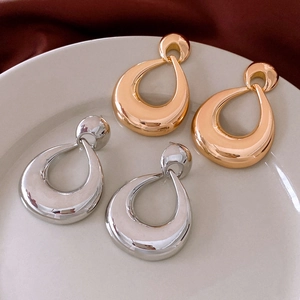Close-up of golden and silver teardrop earrings on a white tray with velvet background