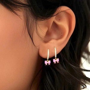 Pink bow pendant earrings with cubic zirconia inlay worn by model for elegant style
