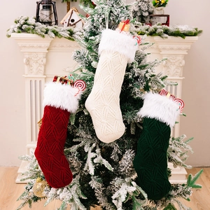 Knitted Christmas stockings in green, red and cream hung on a snowy holiday tree