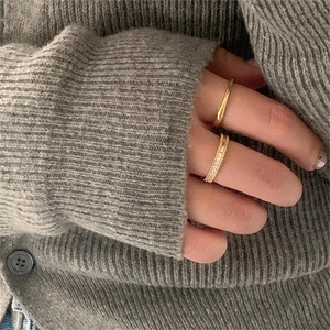 Close-up of minimalist gold 925 sterling silver rings worn on finger against knitwear