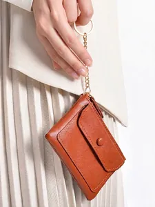 Portable brown leather mini coin purse with gold keychain chain shown on stylish outfit