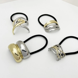 Detail of four bicolor alloy ponytail holders with gold and silver geometric accents