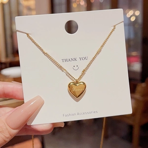Close-up of gold heart pendant engraved with Love on a white Fashion Accessories card