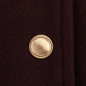 Vue macro des boutons dorés décoratifs sur une veste en laine bordeaux doux