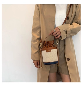 Detail of a brown and beige patchwork bucket bag with drawstring on a model