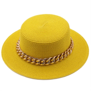 Detail of yellow straw boater hat featuring a decorative thick gold metal chain band