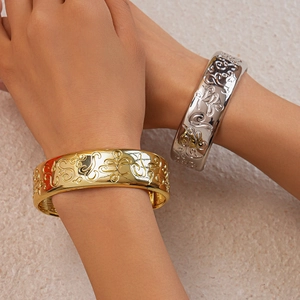 Detailed macro view of embossed vintage floral patterns on gold and silver wide bangles