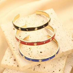 Detailed stack of enamel open bangles in black red and blue with gold star engravings