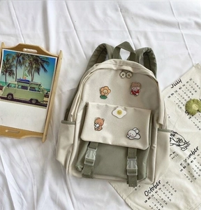 Detail of multi-pocket nylon backpack with cute cartoon pins and contrast stitching
