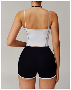 Detailansicht des weißen Yoga-Tops mit schwarzen Trägern und passenden Kontrast-Shorts