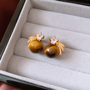 Macro detail of 18K gold plated tiger eye earrings with star zircon in a jewelry box