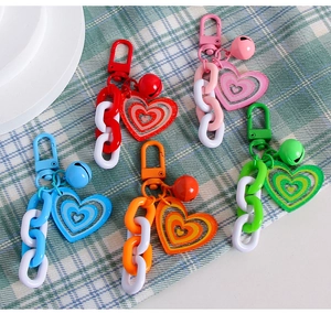 Close-up of five colorful heart-shaped keychains with bells on a checkered background