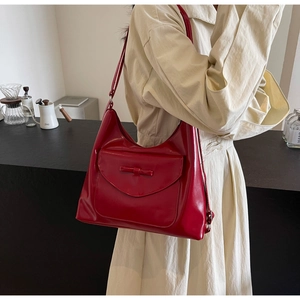 Close-up of red glossy shoulder bag featuring stylish bow detail and front flap pocket