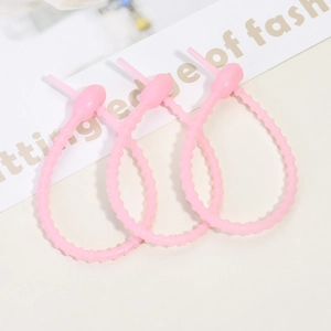 Close-up of three soft pink silicone cable ties with non-slip granular texture design