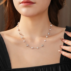 Close-up of a silver flower necklace with zircons and pearls worn by a model