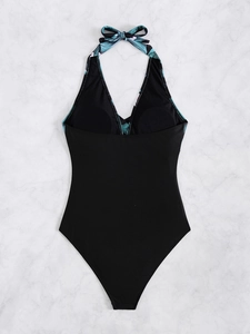 Flat lay of a black halter one-piece swimsuit with tropical leaf print and deep V-neckline