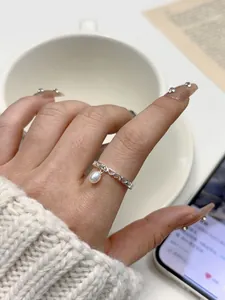 Detail of s925 silver open ring with hollow heart pattern and hanging freshwater pearl