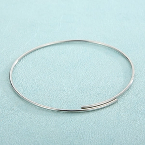 Close-up of minimalist silver stainless steel open bangle with a polished wrap design