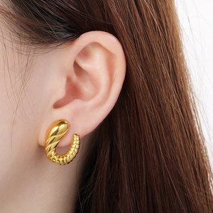 Close-up of a 18K gold plated irregular spiral earring worn by a female model