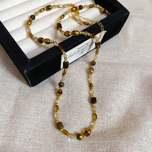 Vue détaillée des perles oeil de tigre vintage et perles dorées sur le collier chic