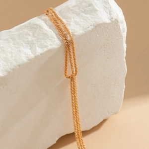 Close-up of a layered gold chain necklace draped over a textured white stone block
