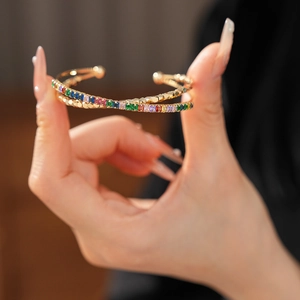Detail of gold crossover bracelet featuring square-cut colorful cubic zirconia stones