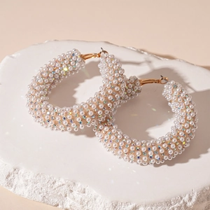 Detail of gold geometric hoop earrings with pearls and crystals on a stone base