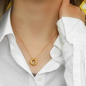 Close-up of a model wearing a 18K gold plated donut pendant necklace with shiny zircons