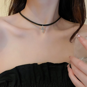 Close-up of black faux leather choker with silver cross pendant on model neck