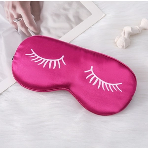 Detail of rose red satin sleep mask featuring white eyelash print on soft plush surface