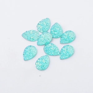 Detailed view of nine teardrop-shaped light blue resin charms with iridescent glitter texture