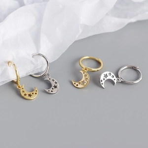 Detailed view of gold and silver moon and star earrings on textured paper background