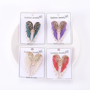 Detailed close-up of four rhinestone angel wing brooches in assorted vibrant enamel colors