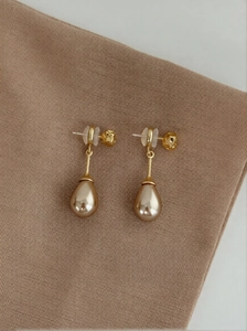 Macro shot of French vintage teardrop pearl earrings with gold-plated metal hooks