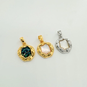 Macro detail of irregular 18K plated pendants with natural shell and hammered texture