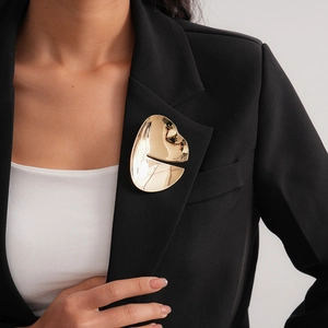 Detail of a minimalist gold irregular geometric brooch on a black suit lapel
