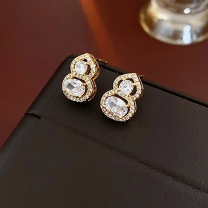Elegant gold gourd pearl earrings with sparkling zircon stones on luxury leather background