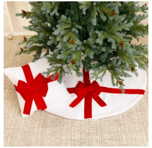Close-up of white plush Christmas tree skirt and pillow set with red velvet bow decor