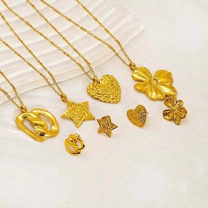 Parure de bijoux dorés avec pendentifs cœur et fleur sur fond blanc texturé élégant