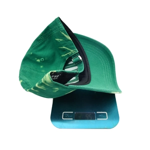 Unisex green tie-dye baseball cap made of cotton fabric shown weighing 95g on a scale
