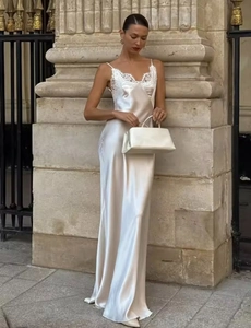 Detailed close-up of white satin dress with lace stitching and matching handbag