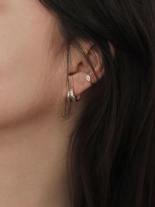 Close-up of layered silver geometric earrings and oval ear cuff set for a modern look