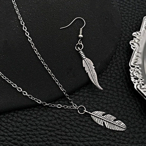 Vintage silver feather jewelry set with necklace and earrings on retro mirror