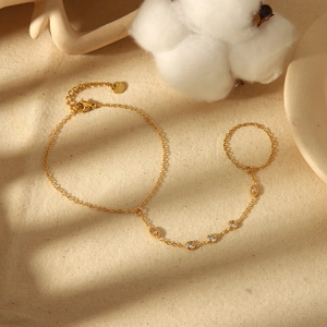 Elegant 18k gold plated finger bracelet with white zircon stones on a beige fabric background