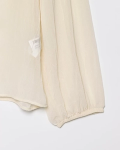Dettaglio del polsino in chiffon beige con pieghe elastiche e consistenza del tessuto